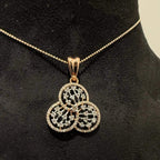 A gold diamond pendant with a floral design, displayed on a black mannequin necklace stand.