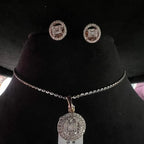A mannequin showcasing a gold diamond pendant and earrings set, with the pendant hanging from a chain and the earrings displayed above.