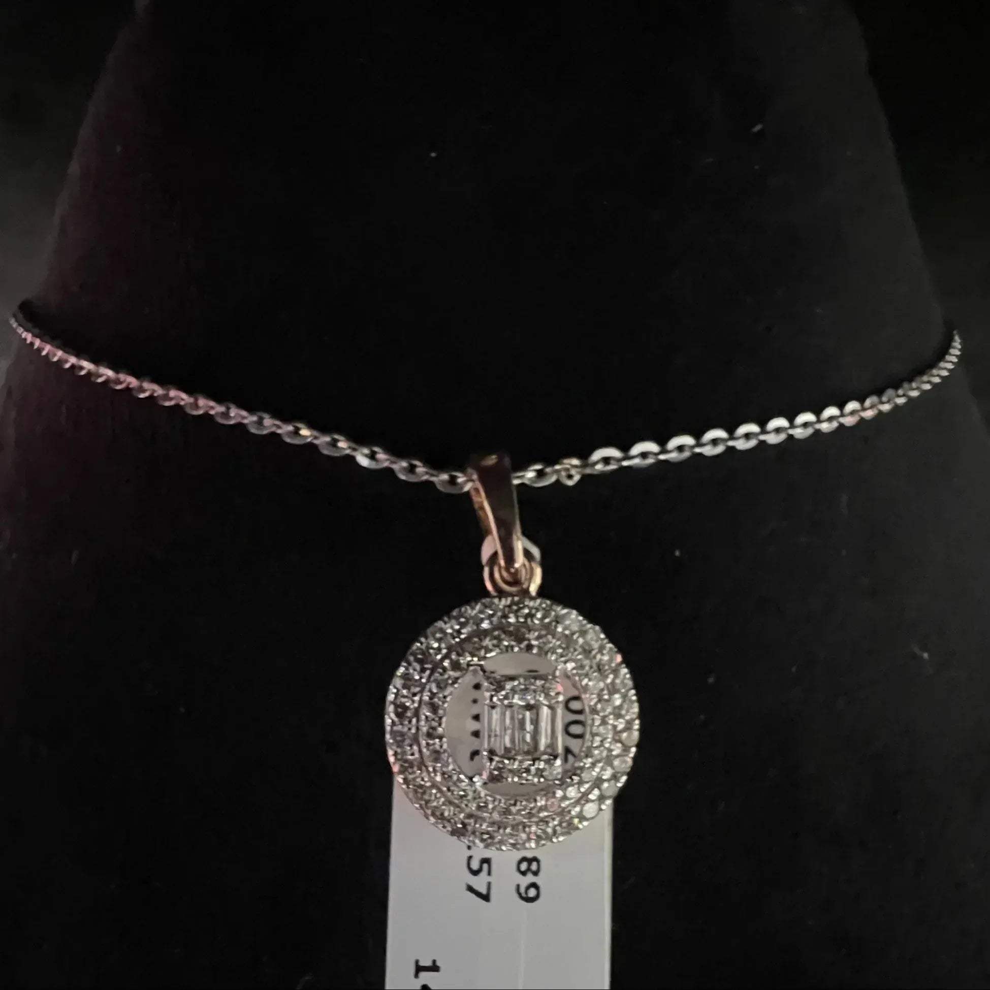 A mannequin showcasing a gold diamond pendant and earrings set, with the pendant hanging from a chain and the earrings displayed above.