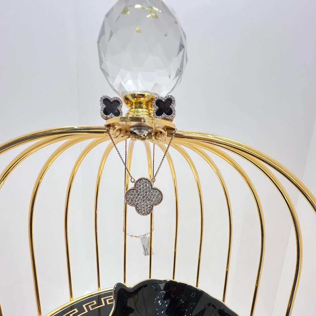 A gold diamond pendant with earrings set, featuring a chain of inset diamonds on a gold-colored metal structure, displayed on a glass stand.