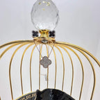 A gold diamond pendant with earrings set, featuring a chain of inset diamonds on a gold-colored metal structure, displayed on a glass stand.