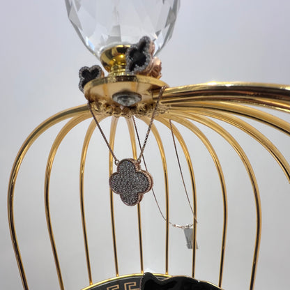 A gold diamond pendant with earrings set, featuring a chain of inset diamonds on a gold-colored metal structure, displayed on a glass stand.