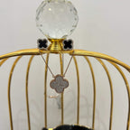 A gold diamond pendant with earrings set, featuring a chain of inset diamonds on a gold-colored metal structure, displayed on a glass stand.