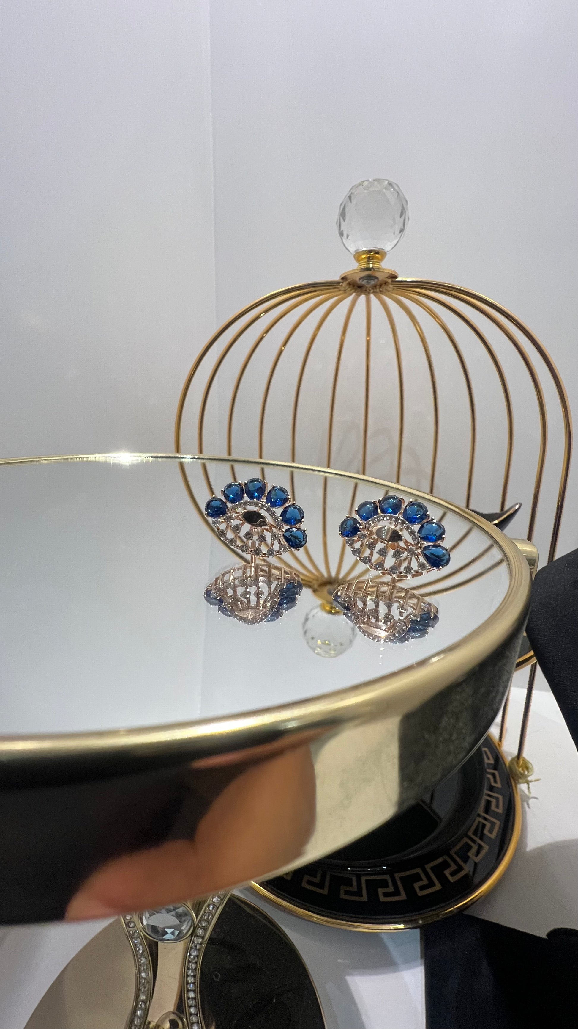gold diamond earrings with blue stones, displayed on a table.