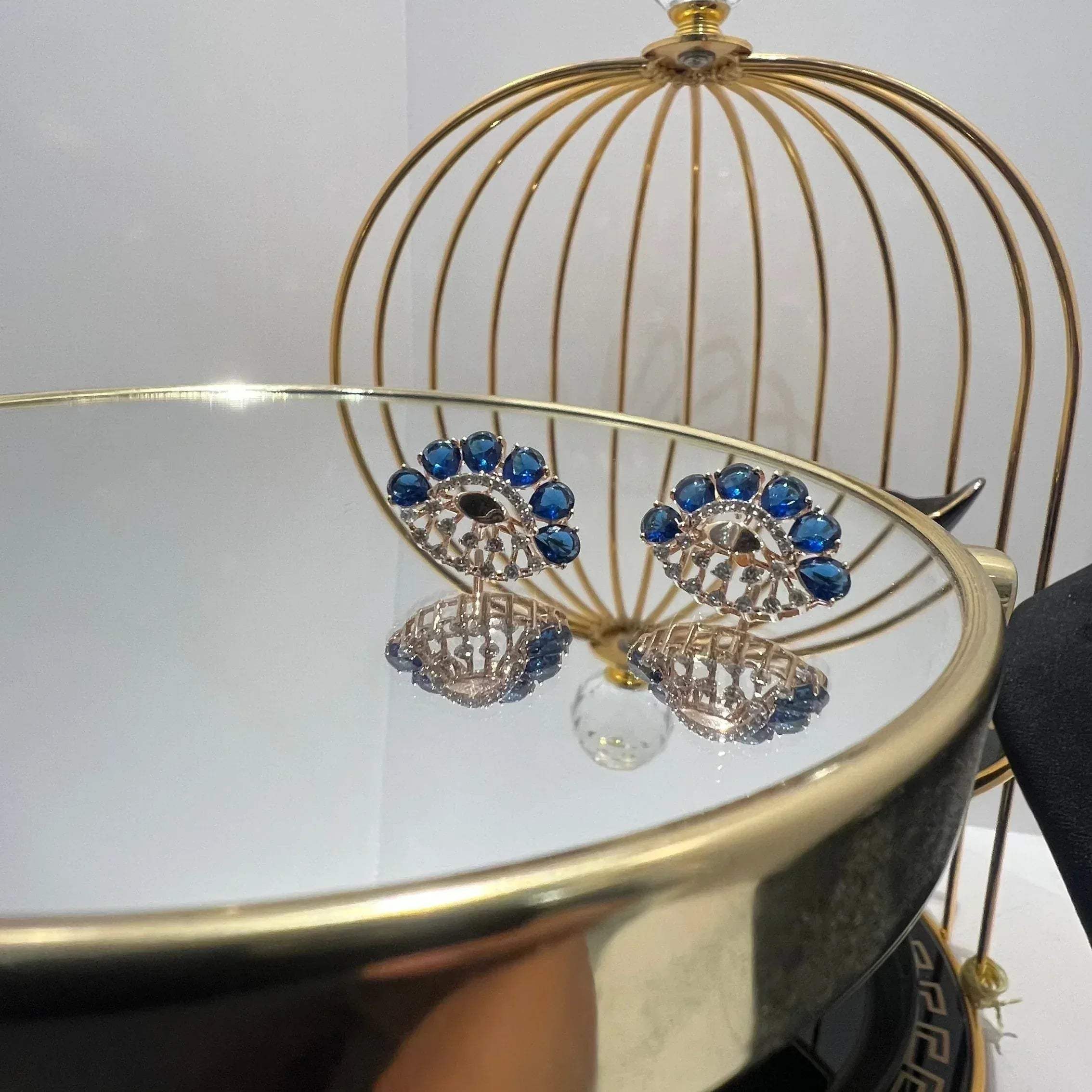 gold diamond earrings with blue stones, displayed on a table.