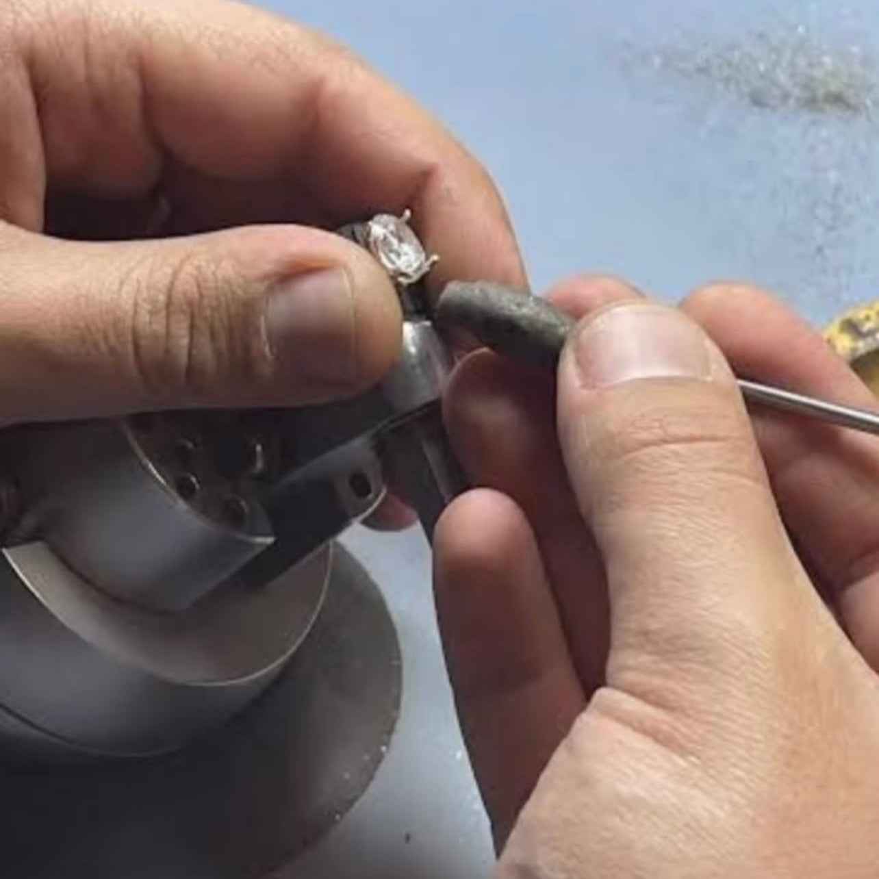 Close-up of hands working on a small mechanical component with a blue background