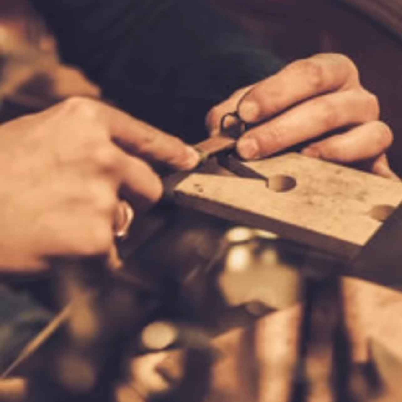 Close-up of hands working with a tool on a wooden block