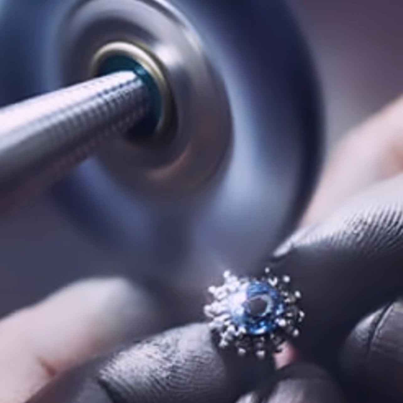 Close-up of a diamond being set into a ring with a lathe in the background