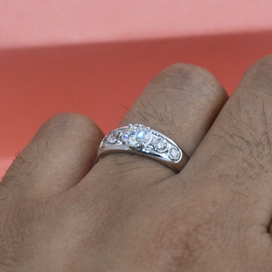 White gold ring with diamonds on a person's finger against a red background