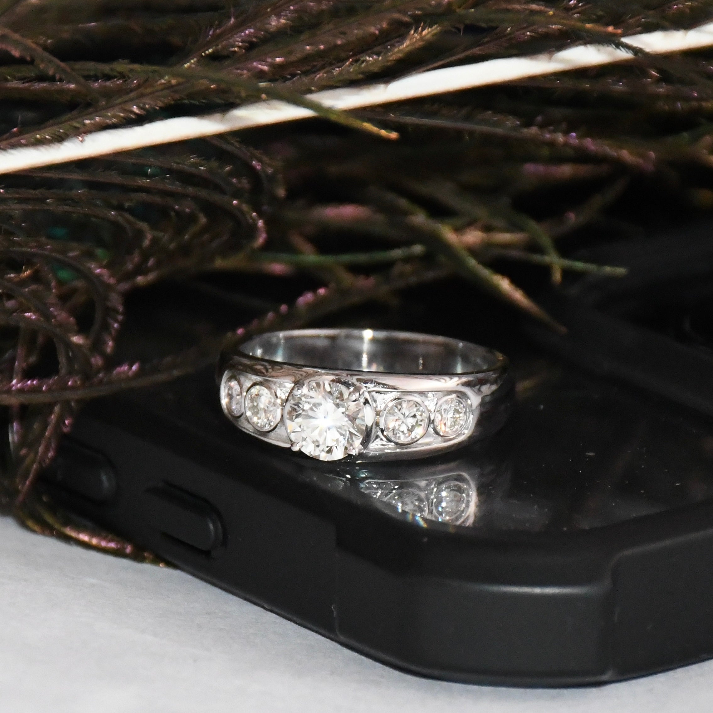 White gold ring with real diamonds on a black phone case with decorative background