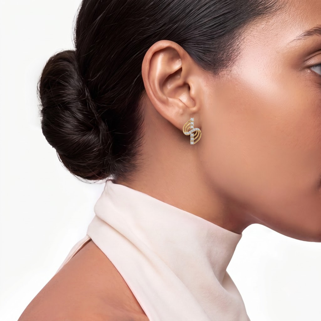 A close-up side profile of a woman with dark hair in a bun, wearing a small gold and diamond stud earring, against a clean white background.