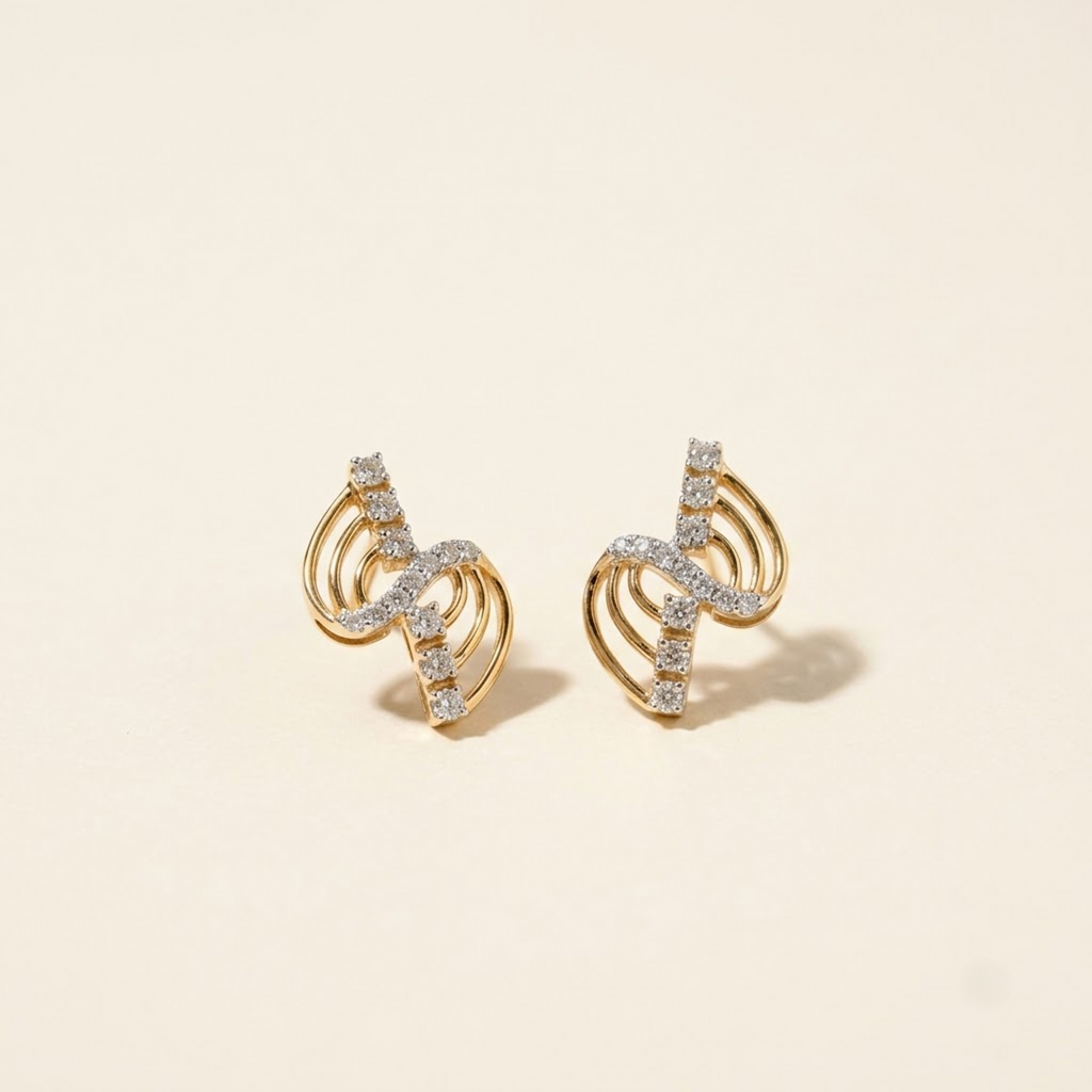 A pair of gold crescent-shaped stud earrings set with small clear stones, displayed on a warm cream background.