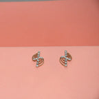 A pair of gold-toned stud earrings with small clear diamonds, displayed on a split pink and peach background.