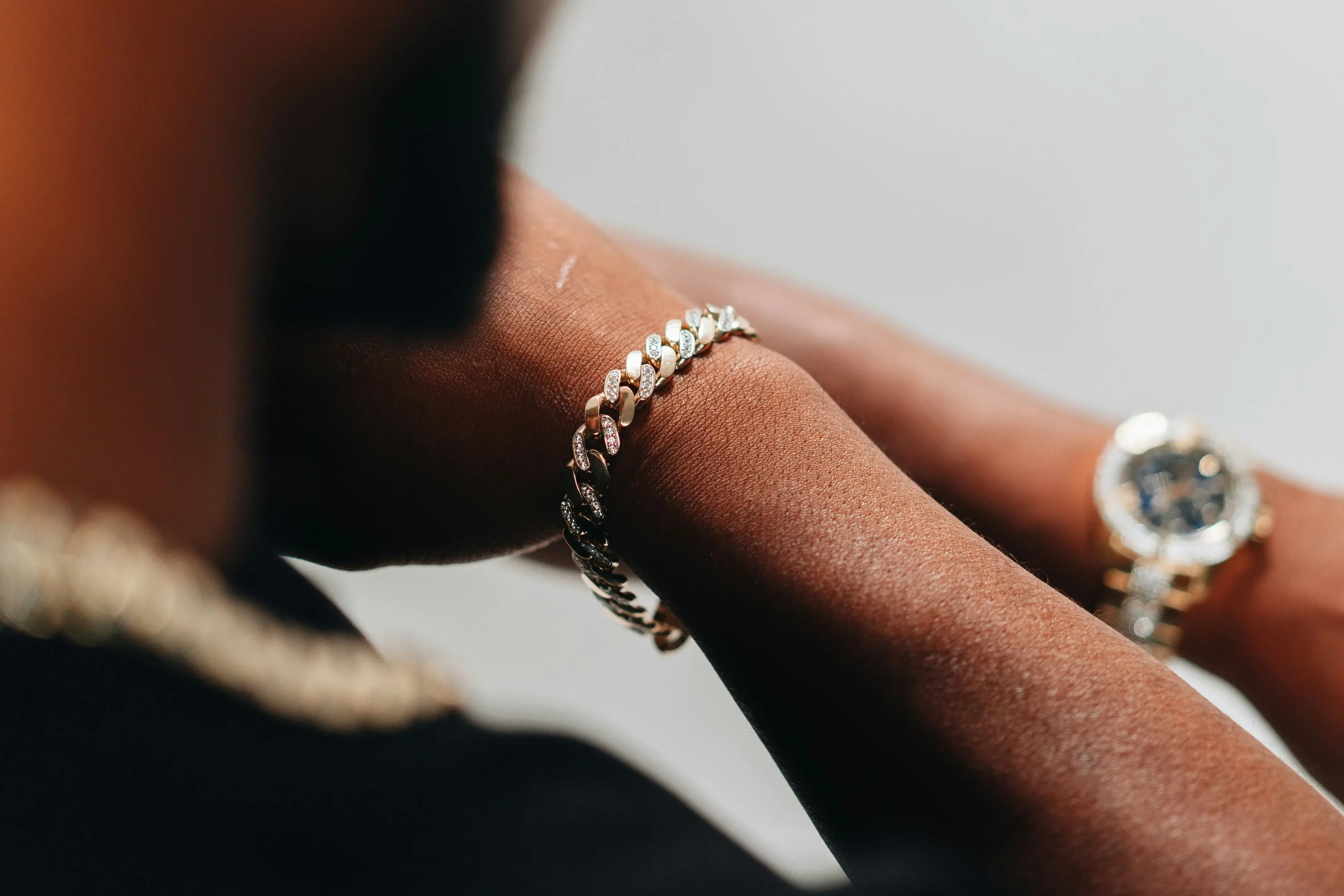 Close-up of a person's arm wearing a bracelet and watch on a neutral background