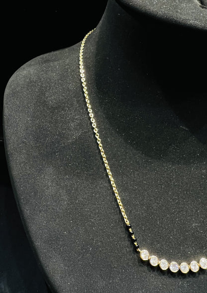 A stylish gold diamond beaded mangalsutra with seven round bezel-set diamonds in a row, paired with small black beads on a delicate gold chain.