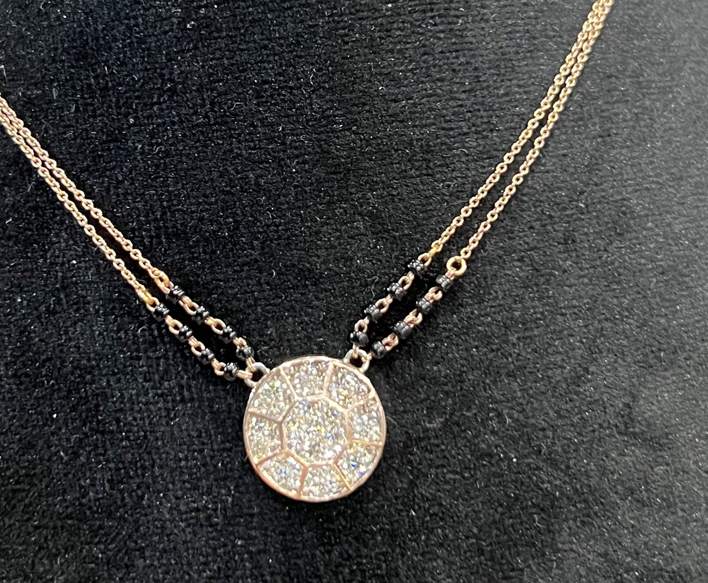 Elegant gold diamond mangalsutra with a circular diamond-studded pendant in honeycomb design, paired with black bead and gold chain for a modern traditional look.