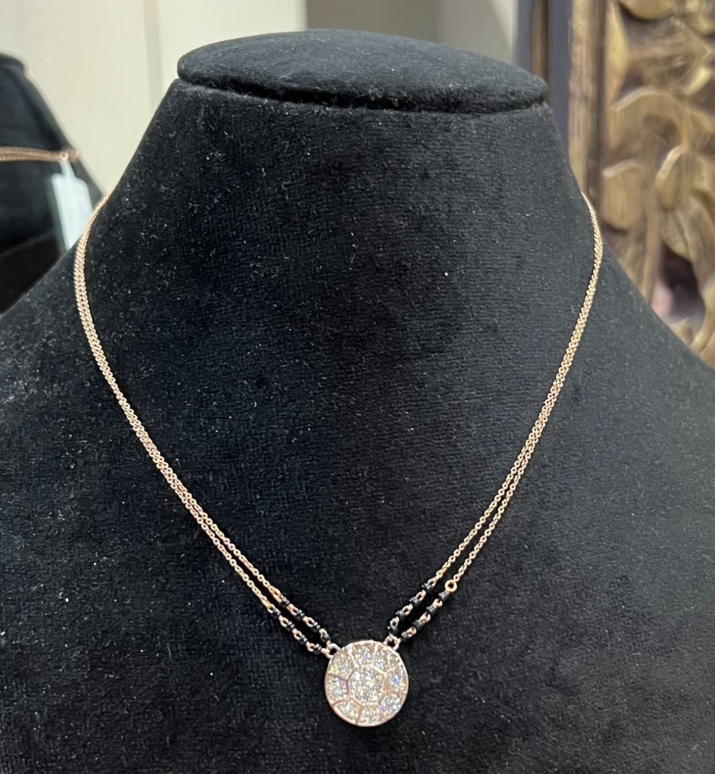 Elegant gold diamond mangalsutra with a circular diamond-studded pendant in honeycomb design, paired with black bead and gold chain for a modern traditional look.