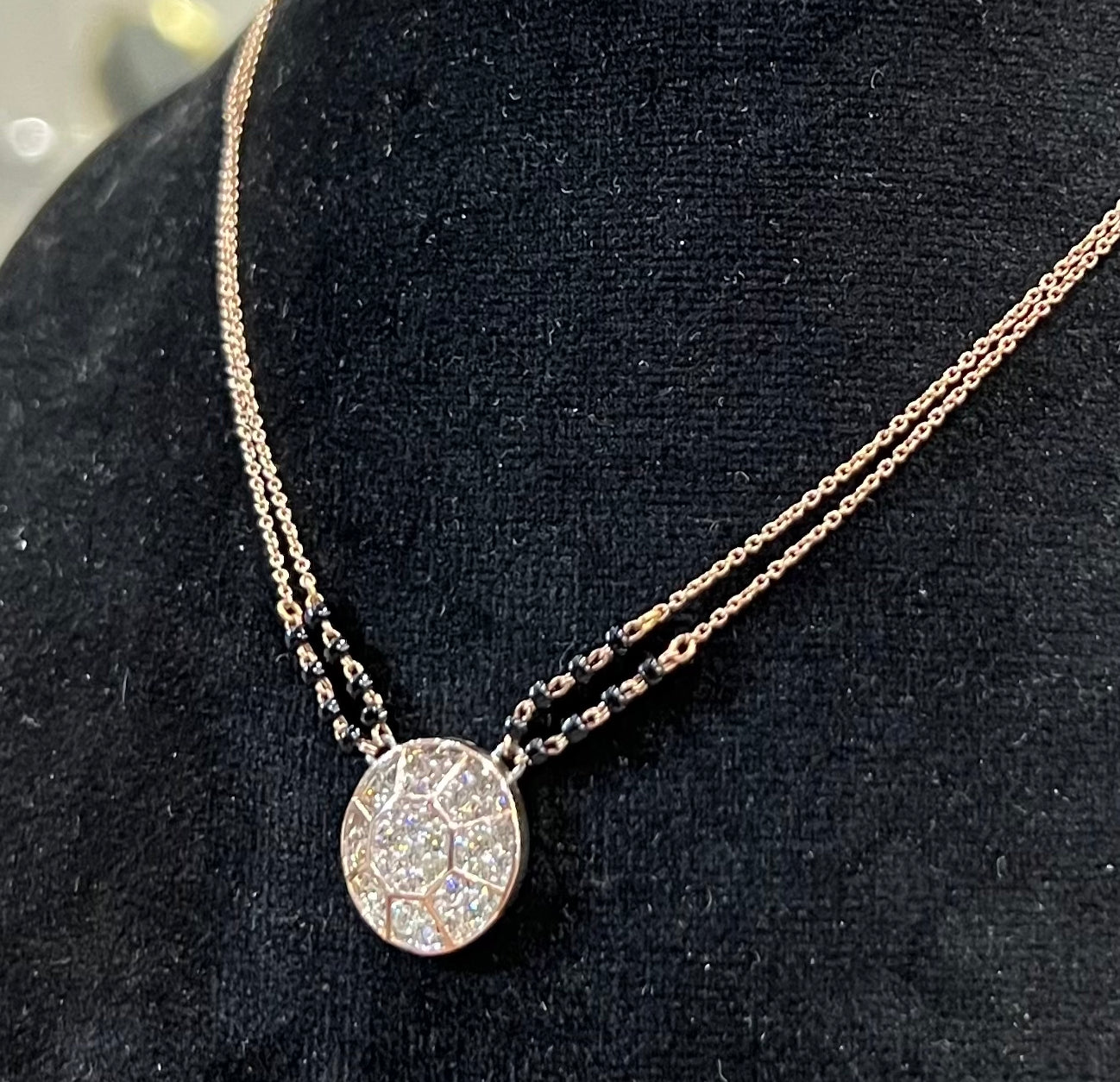 Elegant gold diamond mangalsutra with a circular diamond-studded pendant in honeycomb design, paired with black bead and gold chain for a modern traditional look.