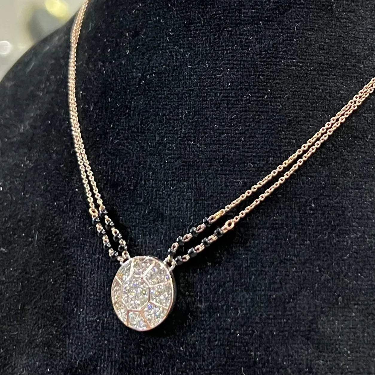 Elegant gold diamond mangalsutra with a circular diamond-studded pendant in honeycomb design, paired with black bead and gold chain for a modern traditional look.