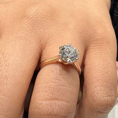 A classic solitaire lab grown diamond ring with a round-cut diamond set in a four-prong gold band, displayed worn in a hand's finger.