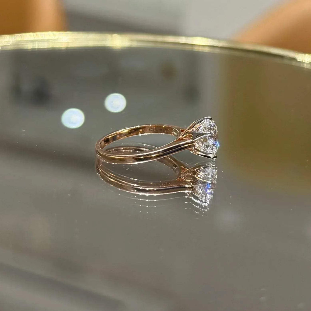 A classic solitaire lab grown diamond ring with a round-cut diamond set in a four-prong gold band, displayed on a reflective surface.