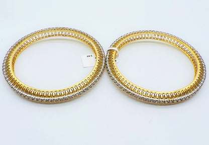 Two gold and lab grown diamond bangles on a white background