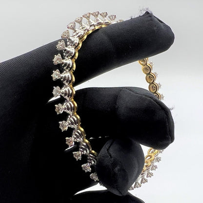 Gold and lab grown diamond bracelet held by a gloved hand against a gray background.