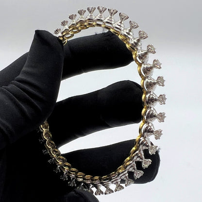 Gold and lab grown diamond bracelet held by a gloved hand against a gray background