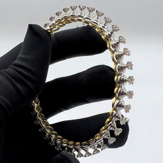 Gold and lab grown diamond bracelet held by a gloved hand against a gray background