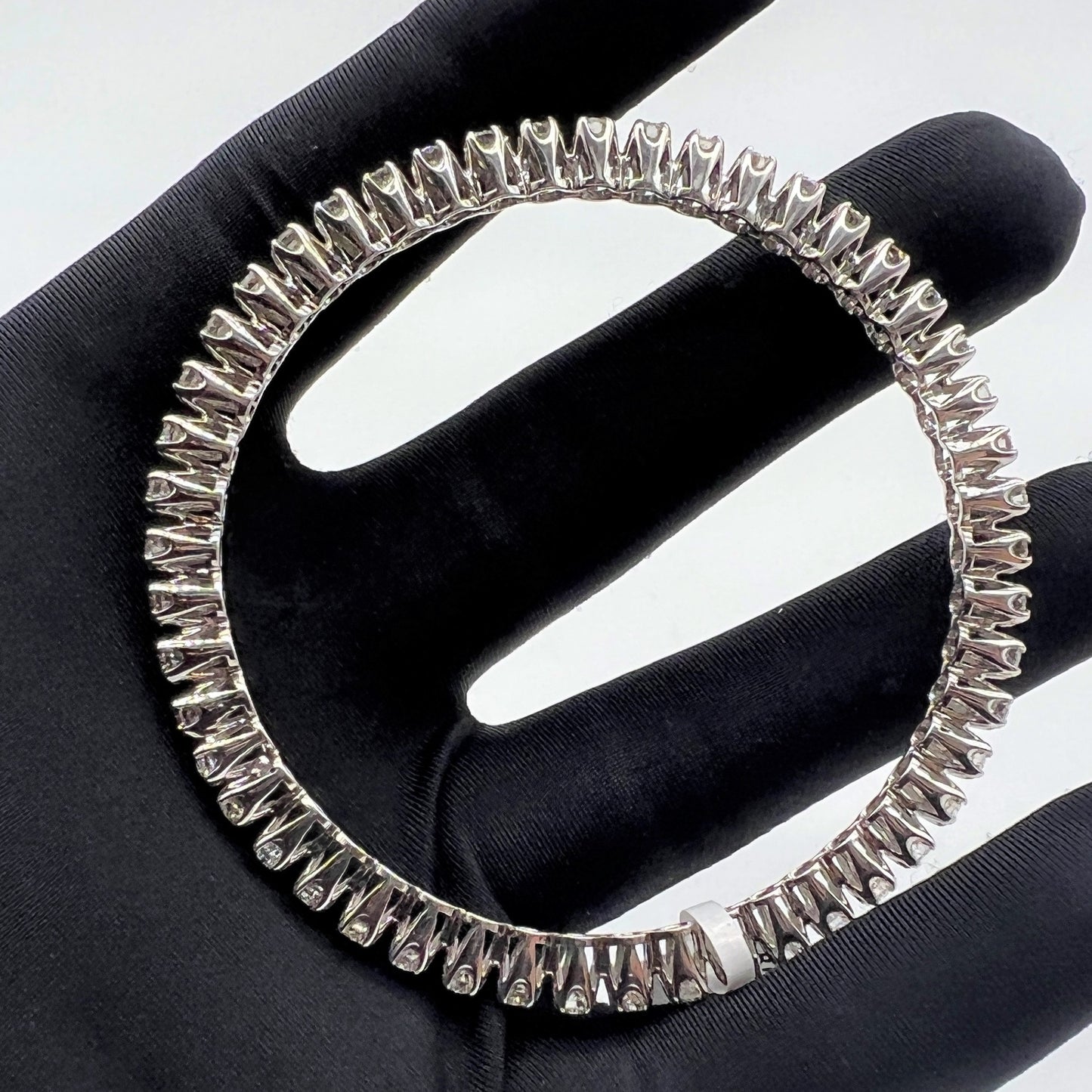 White gold ring with lab grown diamond on a black glove.