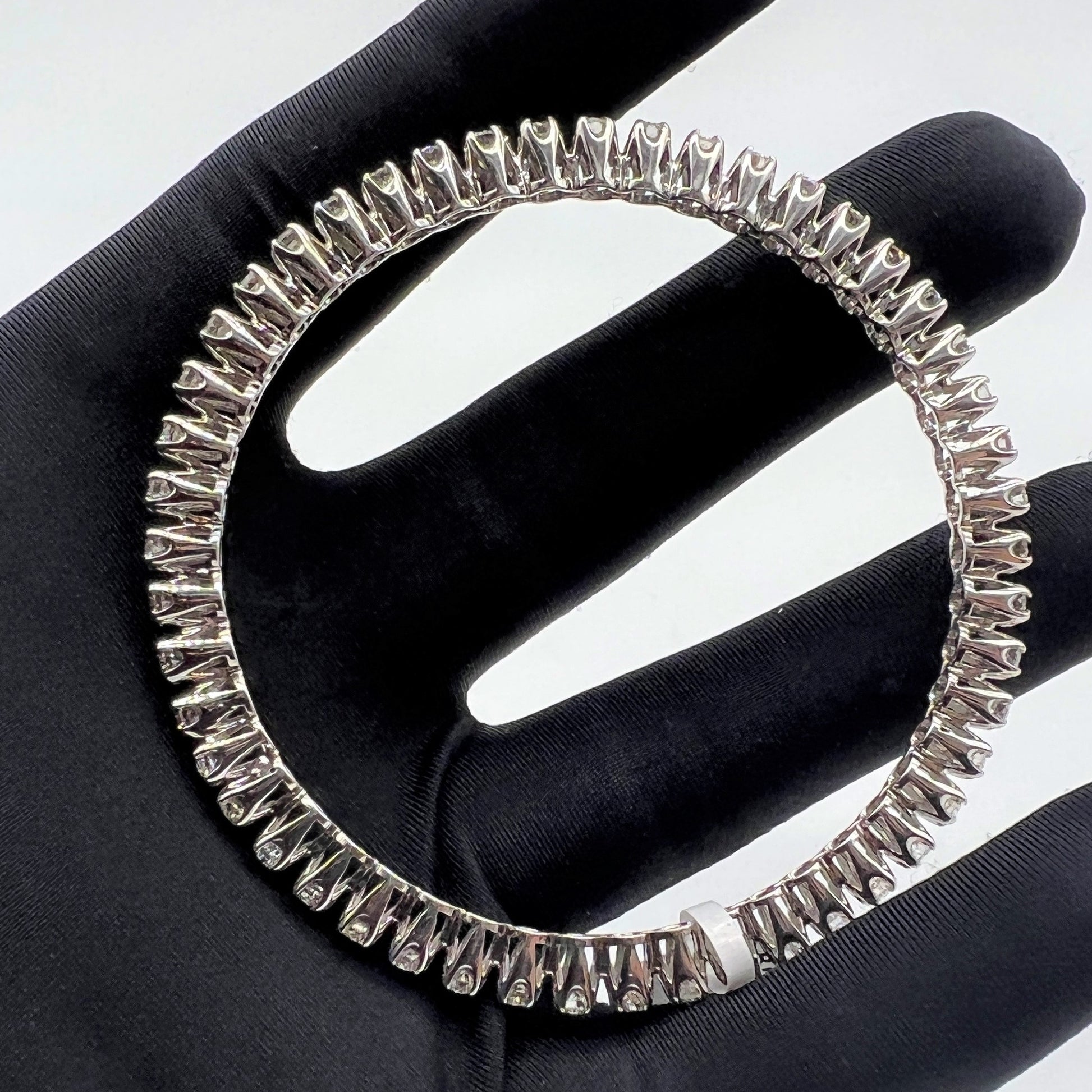 White gold ring with lab grown diamond on a black glove.