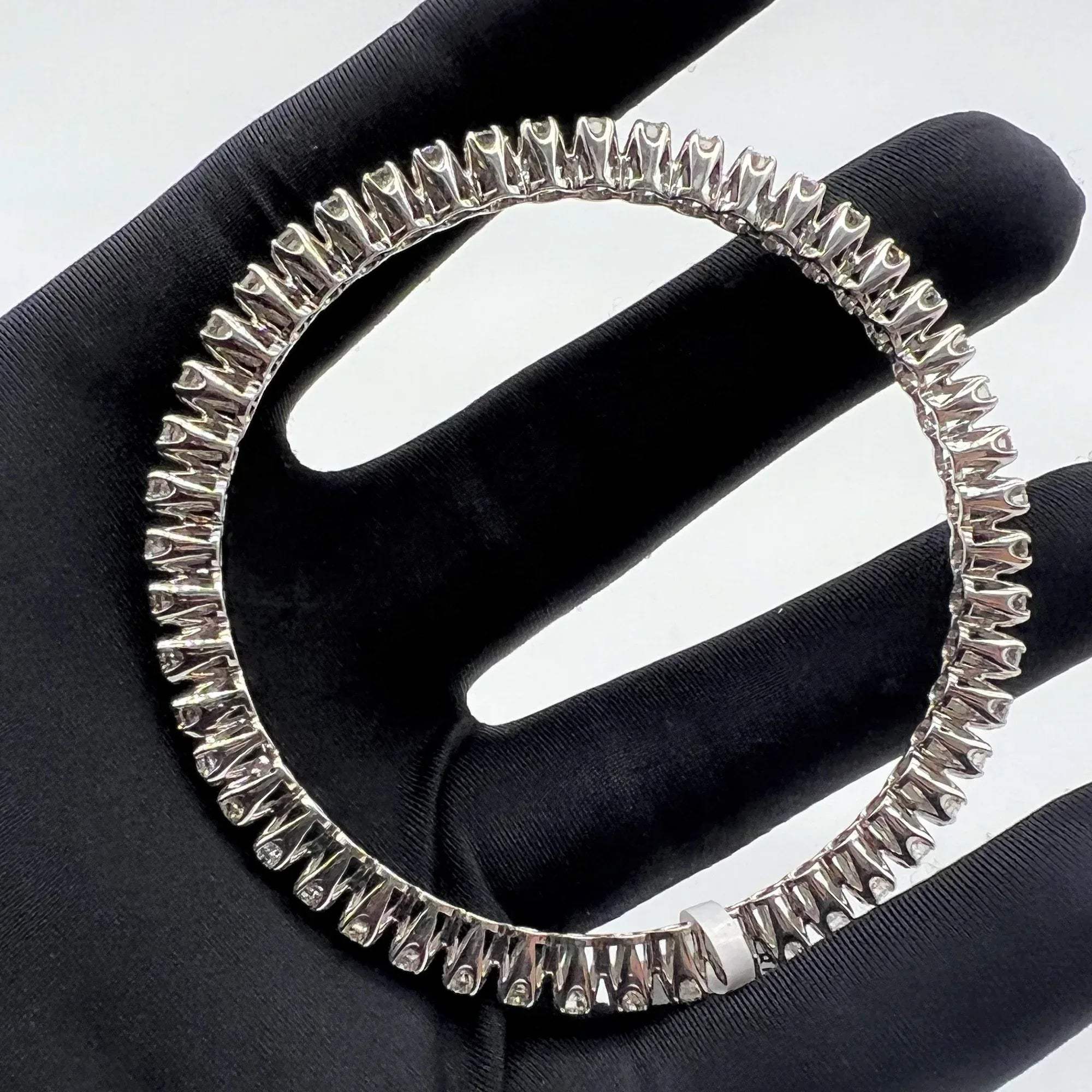 White gold ring with lab grown diamond on a black glove.