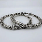 Two white gold and lab grown diamond bangles stacked on a light gray background