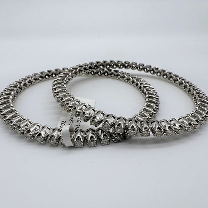 Two white gold and lab grown diamond bangles stacked on a light gray background