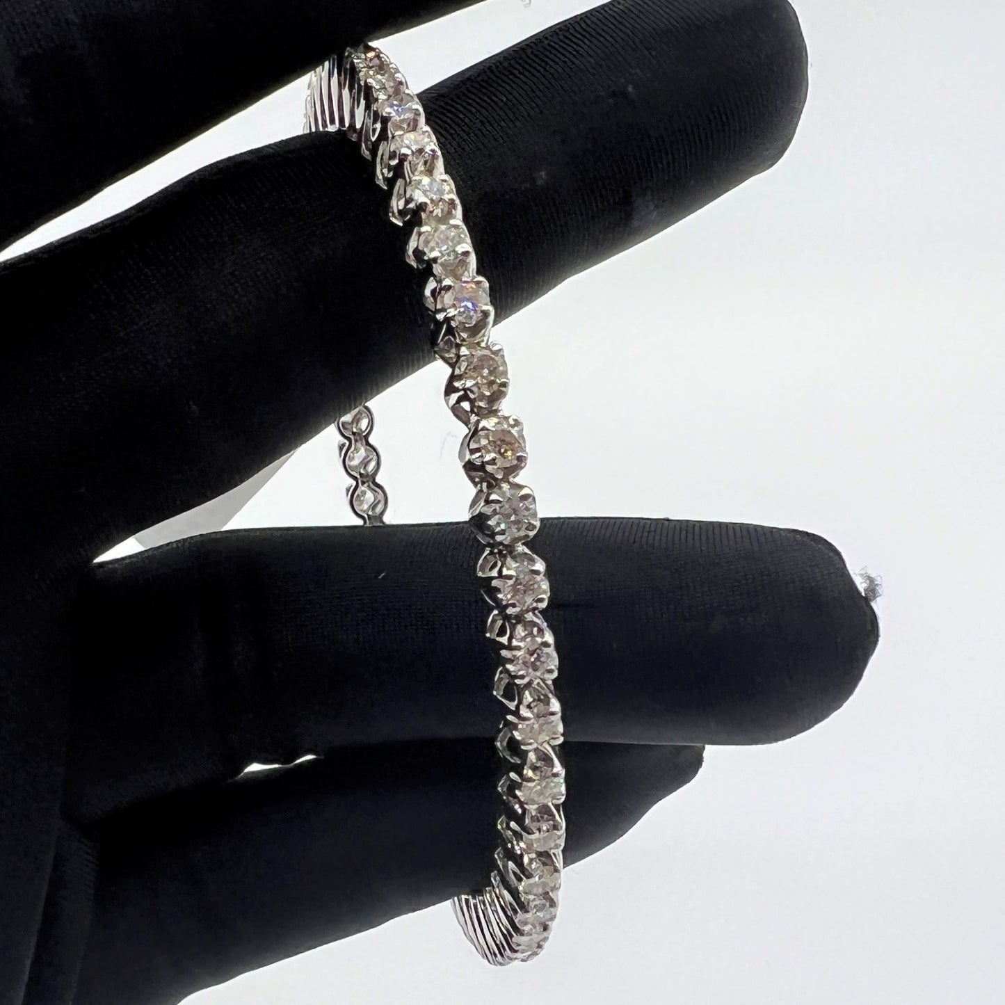 Lab grown diamond bangle held on a black gloved hand against a white background
