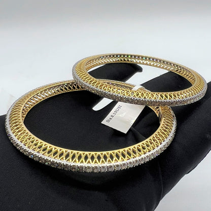 Gold and lab grown diamonds bangles on a black hand with a visible brand tag.