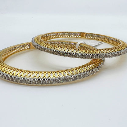 Two gold and lab grown diamond bangles with intricate designs on a white background