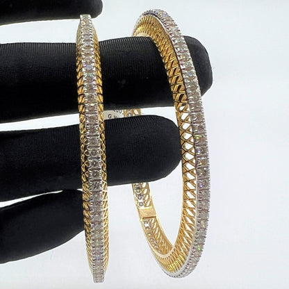 Gold bangles with lab grown diamonds on a black stand against a white background