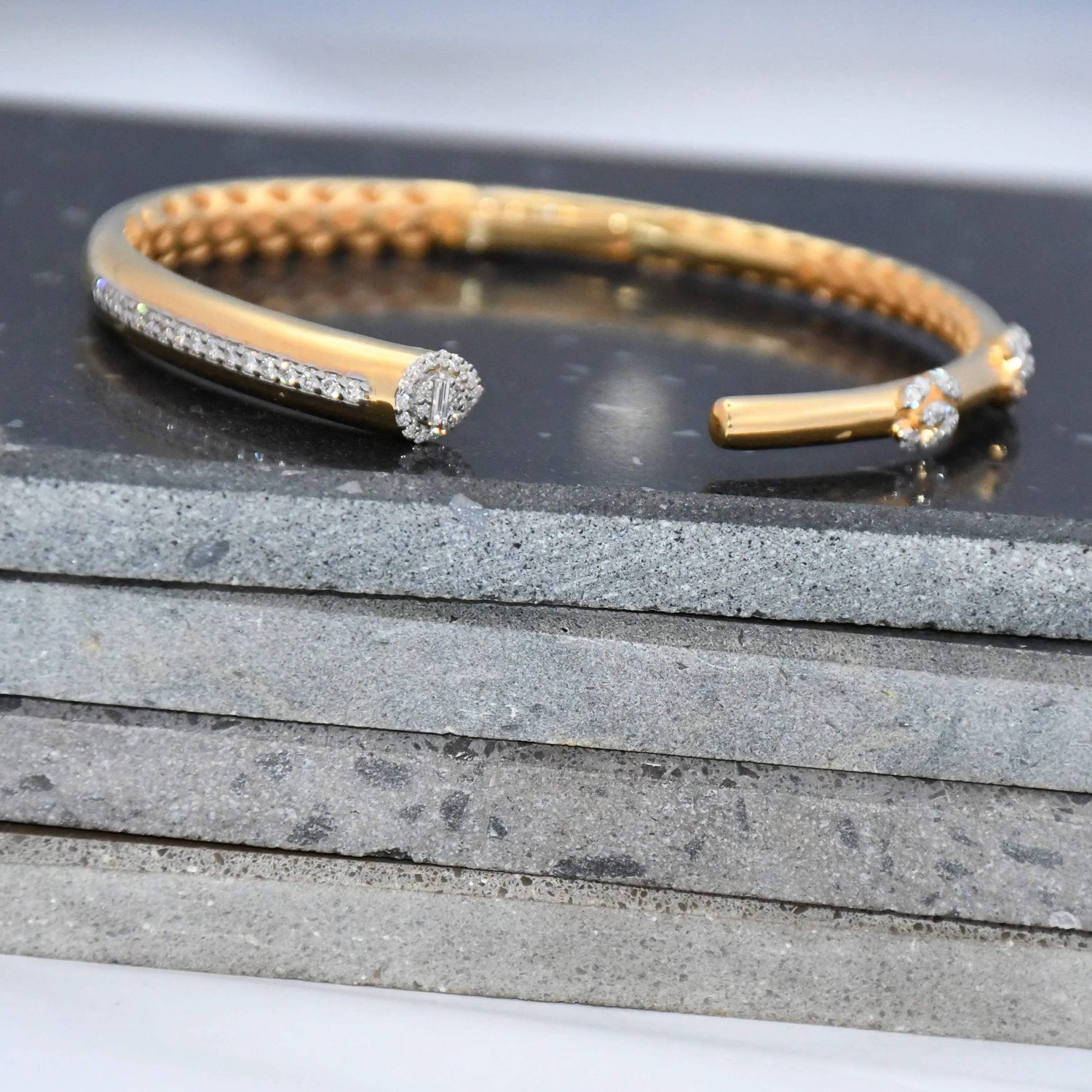 Gold bracelet with lab grown diamonds on a stone surface