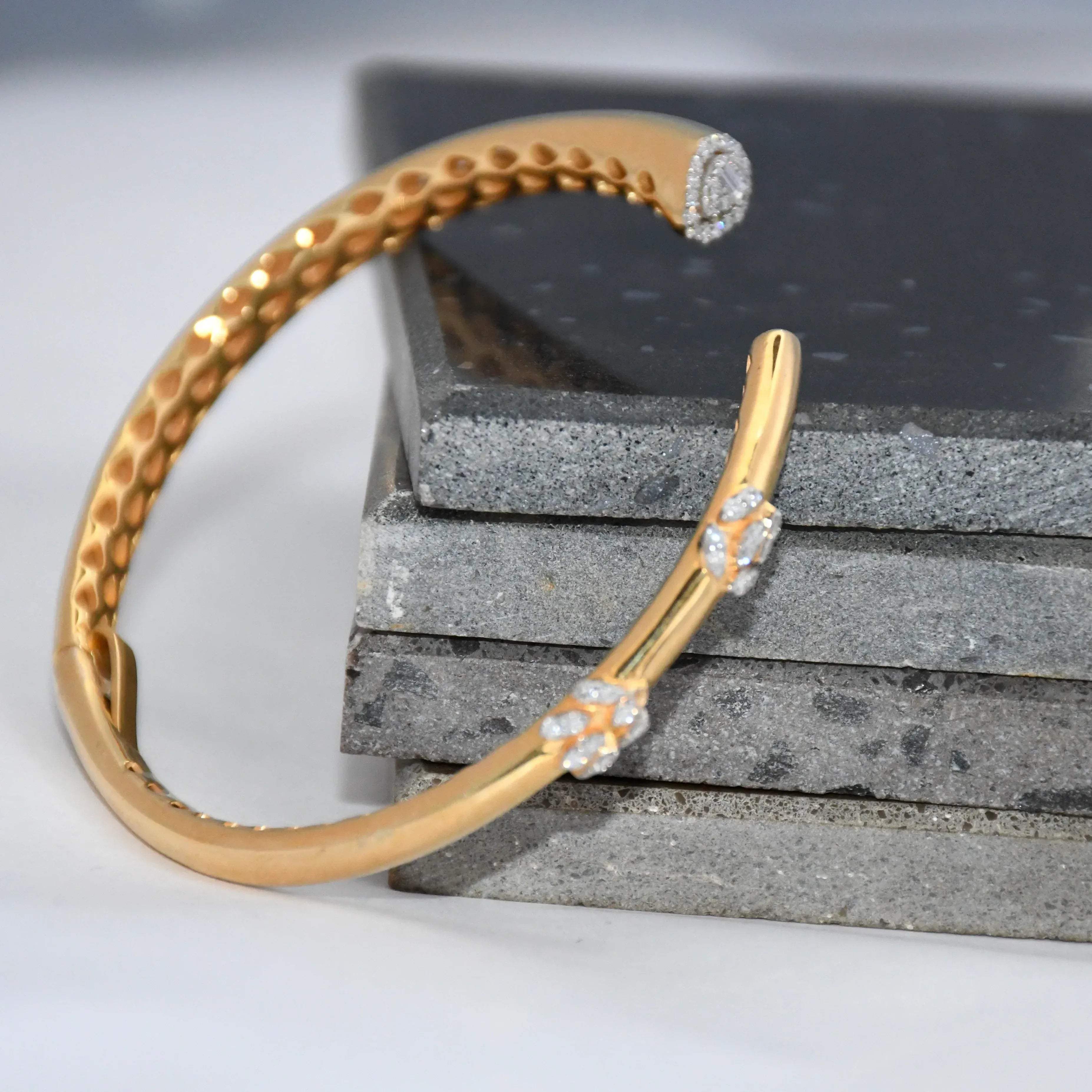 Gold bracelet with lab grown diamond accents on a stone surface