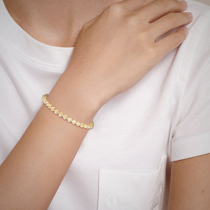 Gold and lab grown diamond bracelet on a person's wrist with a white background.
