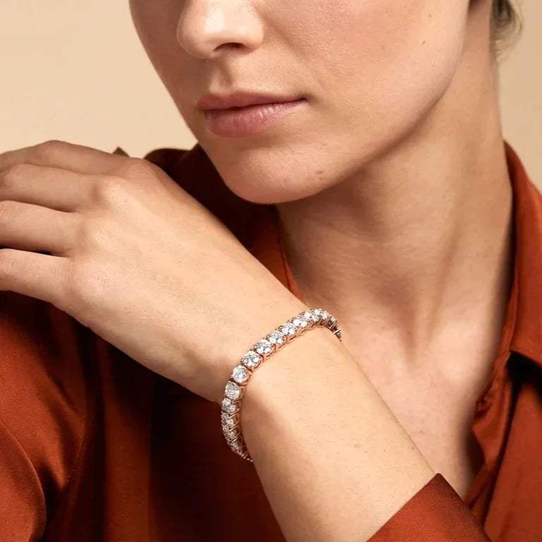 Close-up of a woman's wrist wearing a lab grown diamond bracelet against a beige background
