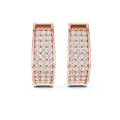 Rose gold huggies/hoops earrings with lab grown diamonds shown on a white surface.
