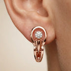 Rose gold earring with a lab grown diamond on an ear against a beige background