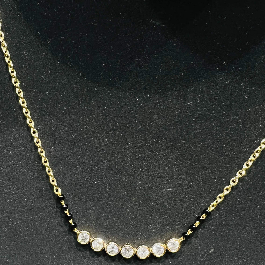 Gold mangalsutra with small round lab grown diamonds on a black background