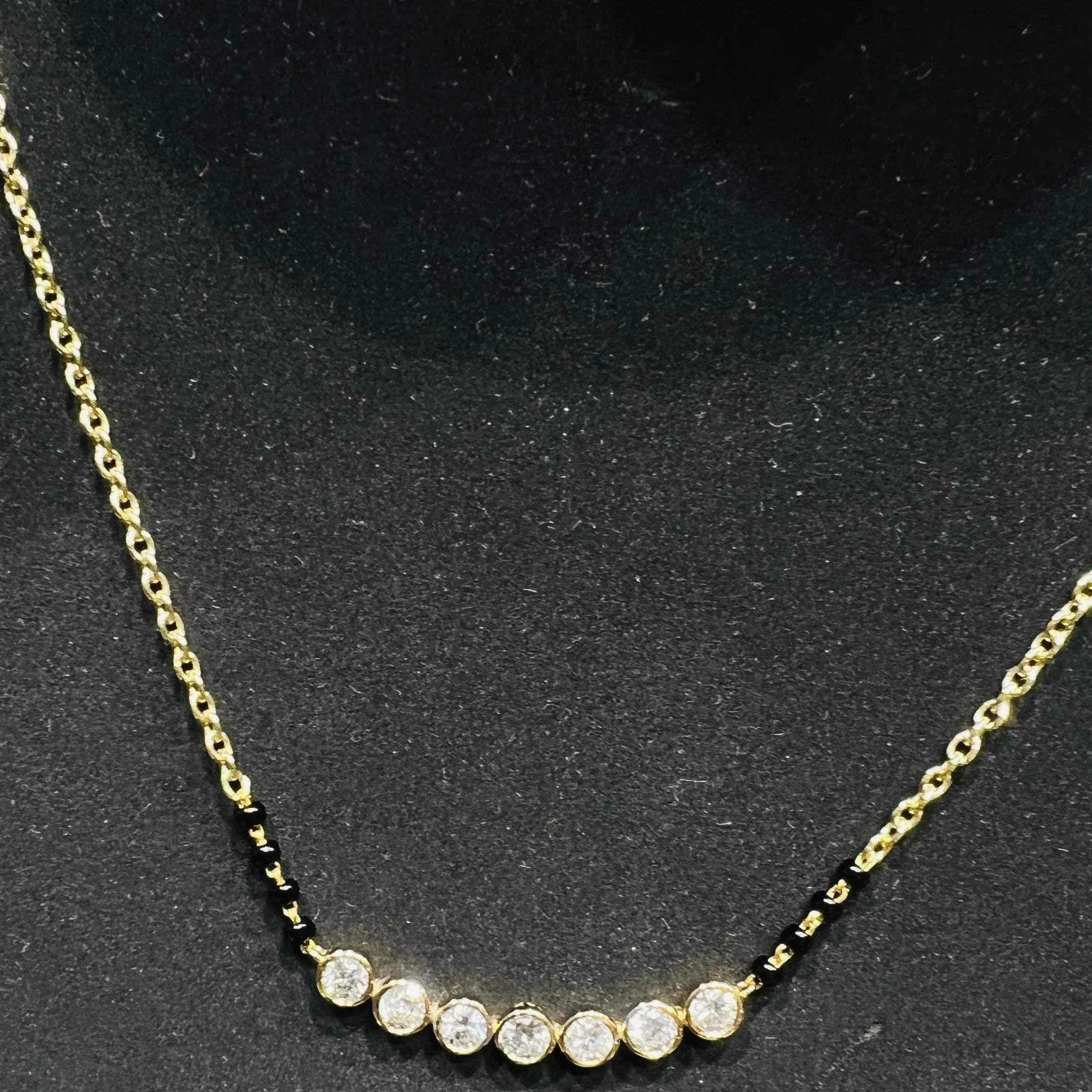 Gold mangalsutra with small round lab grown diamonds on a black background