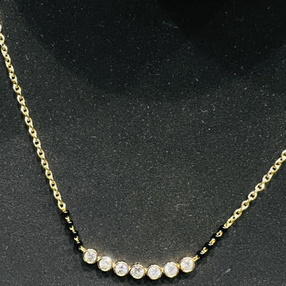 Gold mangalsutra with small round lab grown diamonds on a black background