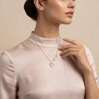 Woman wearing a delicate lab grown diamond necklace with a heart pendant on a beige background