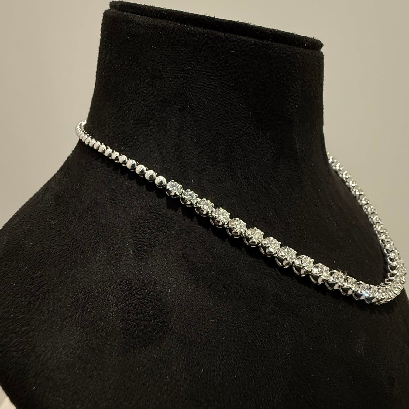 Elegant round cut lab grown diamond necklace set displayed on a black mannequin stand.