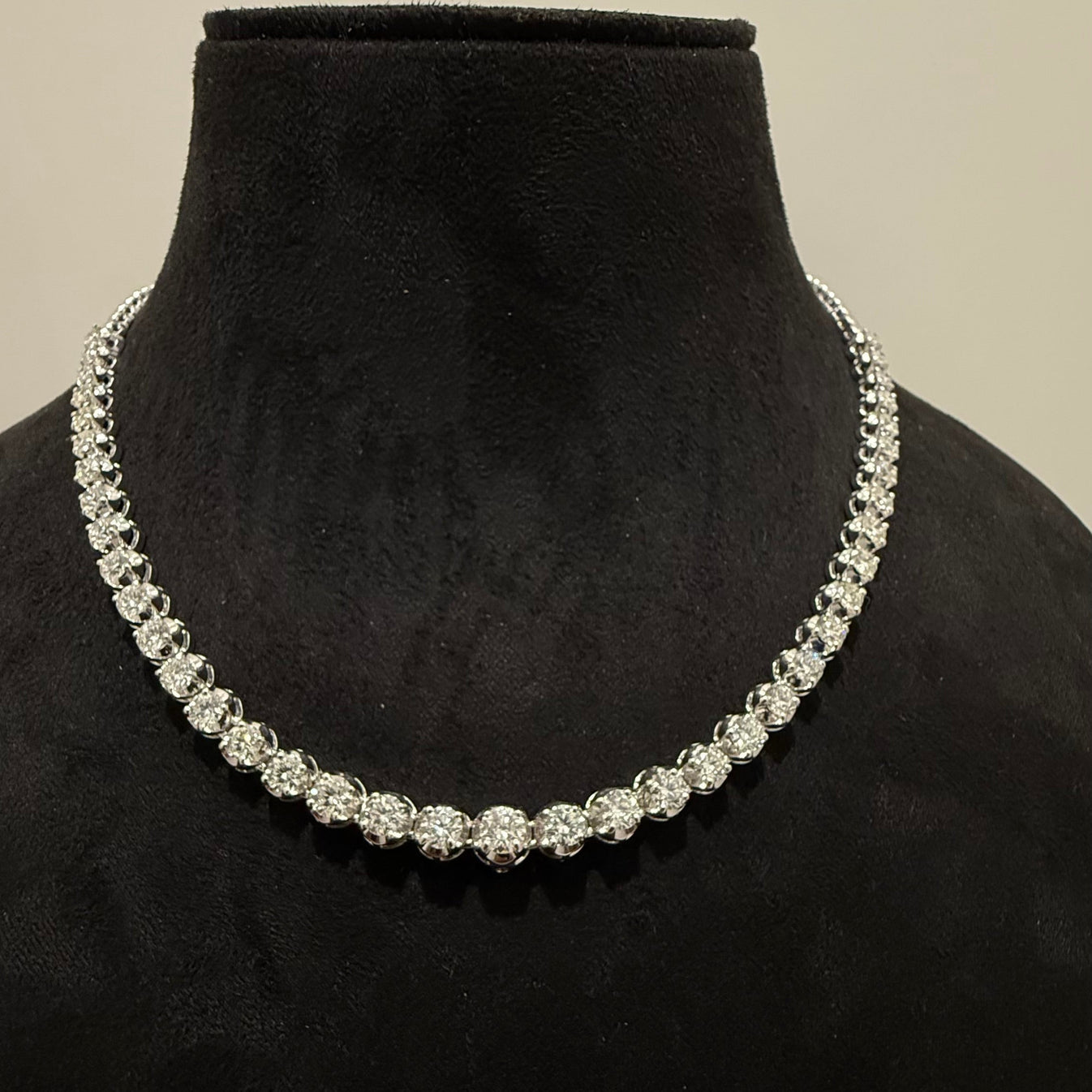 Elegant round cut lab grown diamond necklace set displayed on a black mannequin stand.